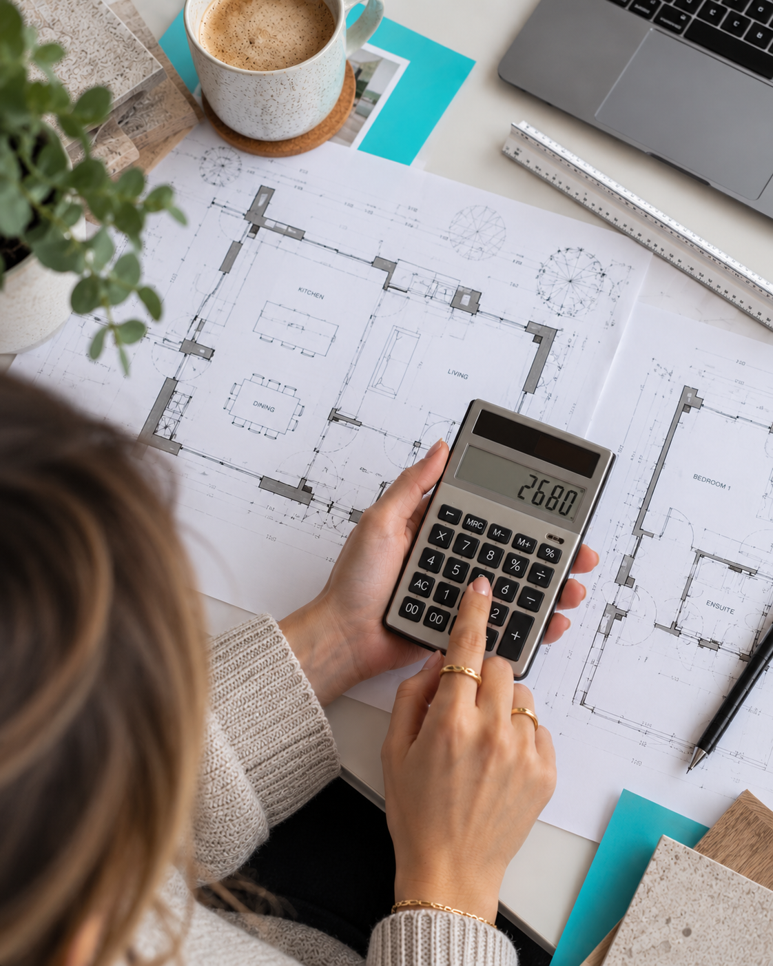 Overhead view of a homeowner using a calculator showing £2,680 while reviewing residential floor plans, with architectural drawings, material samples and turquoise Design Spec accents on the desk.