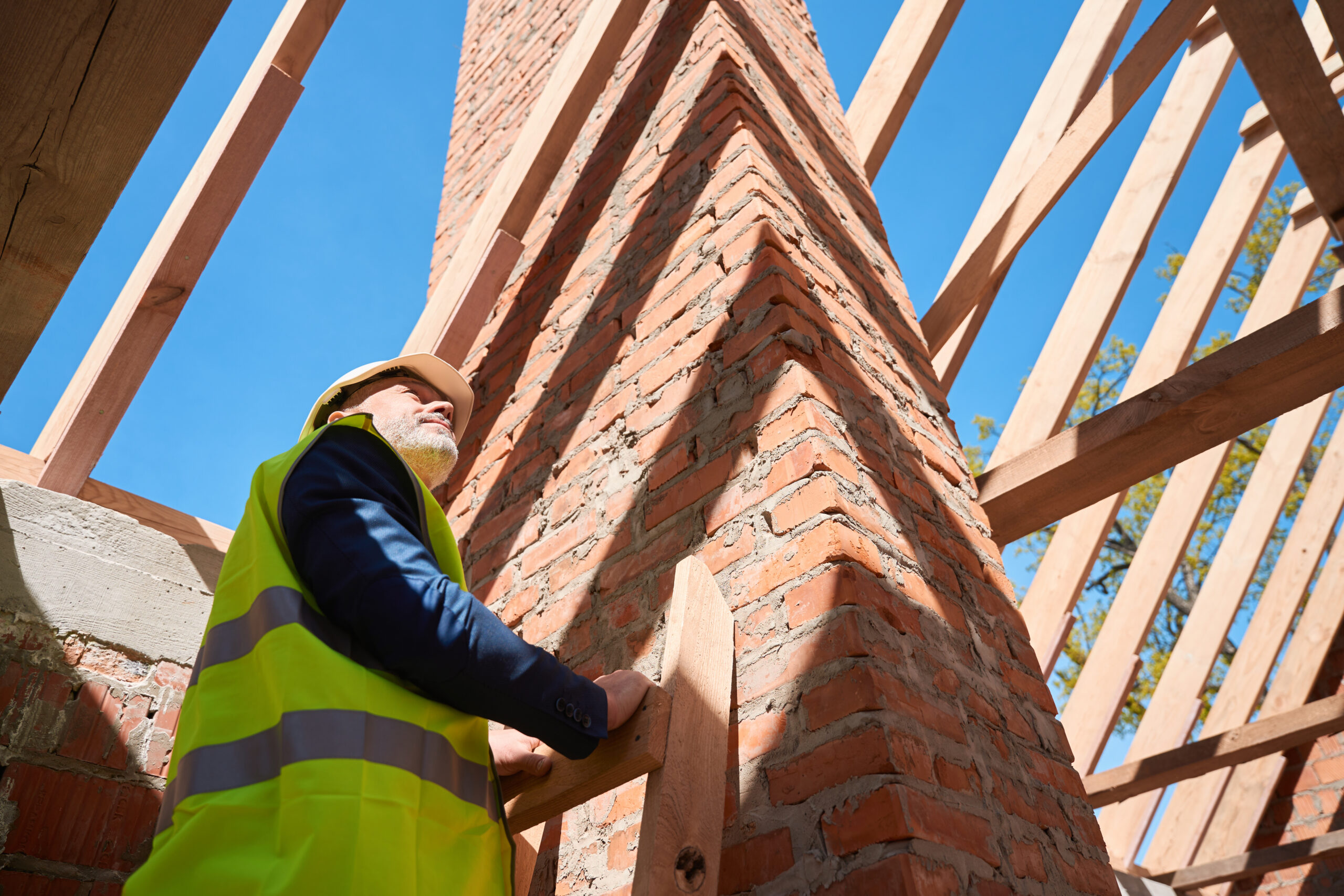 Building engineer standing on ladder looking at roof beams